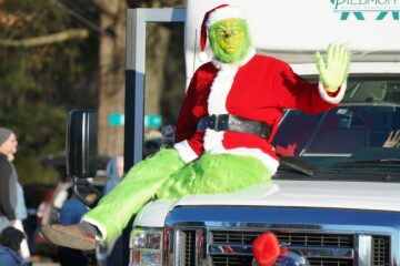 Eine als Grinch verkleidete Person sitzt auf der Motorhaube eines Trucks